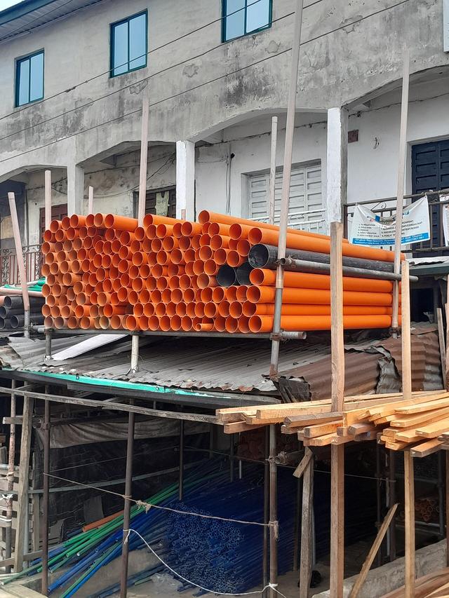 Stacks of orange and grey plastic pipes on a building site