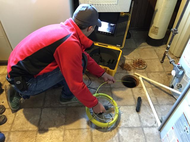 Drain inspection camera being lowered into a floor drain to check the pipe