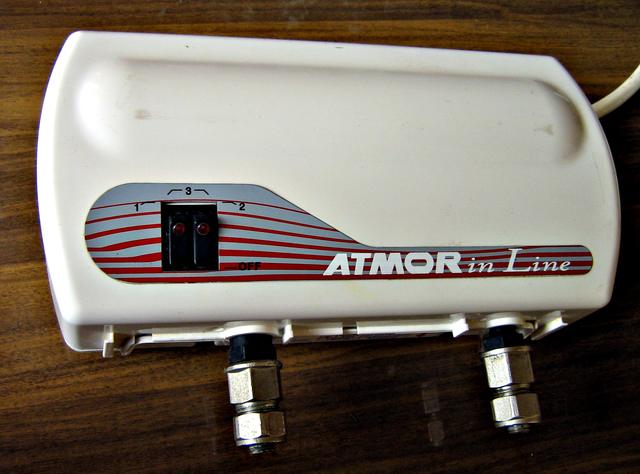 Compact white electric instantaneous water heater mounted on a wall