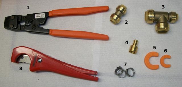 Pipe cutter, crimping tool and brass fittings laid out for a water pipe repair